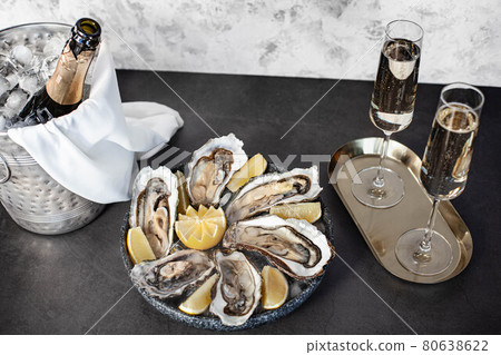 Champagne glasses with sparkling wine and bottle in bucket near oysters Champagne glasses with sparkling wine and bottle in bucket near oysters 80638622