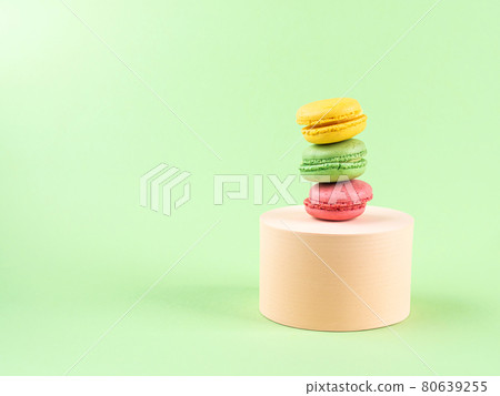 Geometric pastel green background with colorful macaroon sweet candies on circle podium 80639255