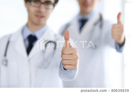 Two male doctors standing as a team and showing thumbs up as a symbol of the best service for patients in the clinic. Medicine and health care Two male doctors standing as a team and showing thumbs up as a symbol of the best service for patients in the clinic. Medicine and health care 80639839