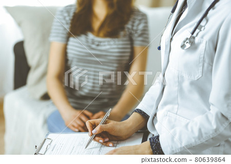 Unknown woman doctor and patient discussing current health examination while sitting in cozy living room. Stay at home concept during Coronavirus pandemic and self isolation quarantine 80639864