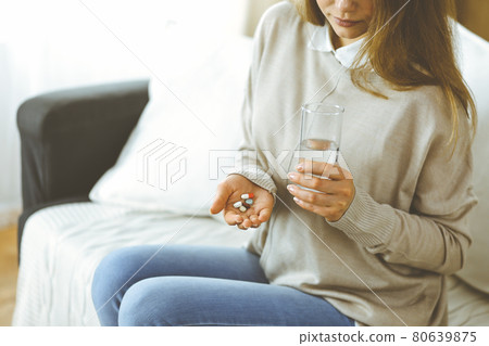 Close-up woman holding pills time to take medications, cure for headache, high blood pressure pain killer drugs at home. Stay at home concept during Coronavirus pandemic 80639875