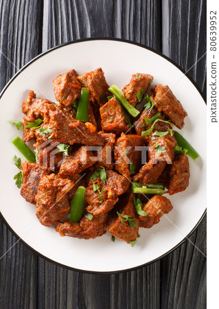 Tibs is a popular Ethiopian dish of sauteed beef flavored with niter kibbeh and berbere closeup in the plate. Vertical top view 80639952