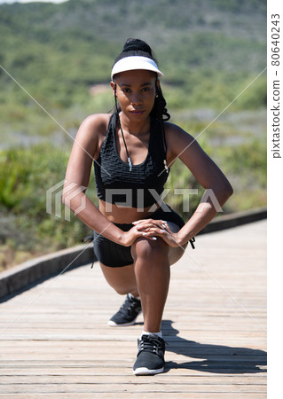 Focused afro american woman stretching while looking at the camera: Running and exercise concept. Focused afro american woman stretching while looking at the camera: Running and exercise concept. 80640243