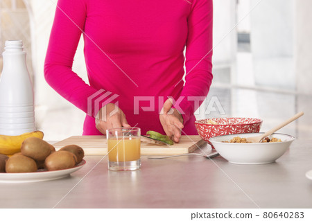 Unrecognizable woman putting in a bowl the pieces of kiwi she has just cut up Unrecognizable woman putting in a bowl the pieces of kiwi she has just cut up 80640283