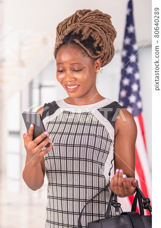 African American woman using phone and holding handbag African American woman using phone and holding handbag 80640289