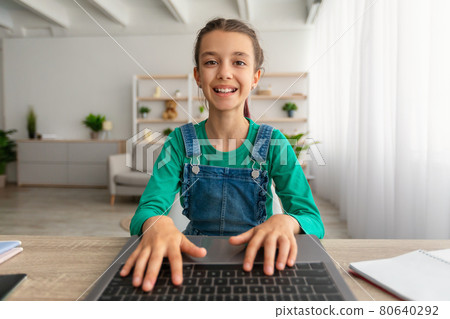 Girl sitting at desk, using laptop, typing on keyboard Girl sitting at desk, using laptop, typing on keyboard 80640292