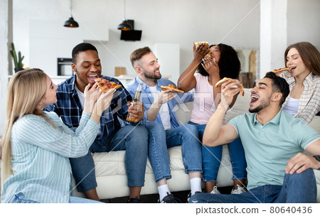 Positive diverse friends having home party, sitting on sofa, eating pizza with beer, having fun together 80640436
