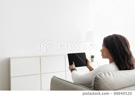 Smart home concept. Millennial woman using digital tablet with blank screen, adjusting house automation processes Smart home concept. Millennial woman using digital tablet with blank screen, adjusting house automation processes 80640520