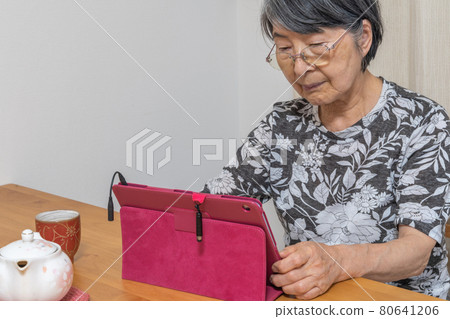 An old Japanese woman enjoying the Internet using a tablet device An old Japanese woman enjoying the Internet using a tablet device 80641206