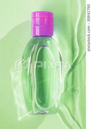 Small green transparent bottle with pink cup, on green background with water, top view Small green transparent bottle with pink cup, on green background with water, top view 80642760