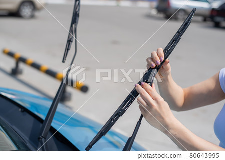 Faceless woman changing car windshield wipers. 80643995