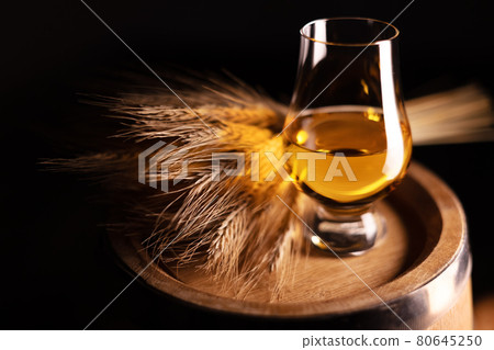 A glass of whiskey on oak barrel 80645250