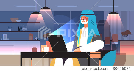 senior arab businessman freelancer working on laptop arabic man sitting at workplace in dark night home room senior arab businessman freelancer working on laptop arabic man sitting at workplace in dark night home room 80646025