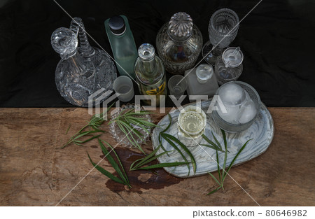 Ice cold Marijuana cannabis CBD infused drink in a crystal clear glass with green marijuana leaf on wooden background. 80646982