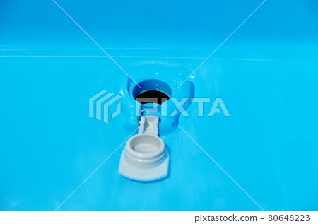 The sight of opening the white drain cap on the bottom of the blue basin and draining the water The sight of opening the white drain cap on the bottom of the blue basin and draining the water 80648223
