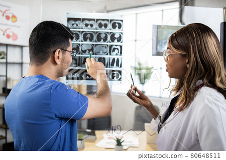 Two multiracial colleagues look and discuss an X-ray or MRI scan of the patient, close up Two multiracial colleagues look and discuss an X-ray or MRI scan of the patient, close up 80648511