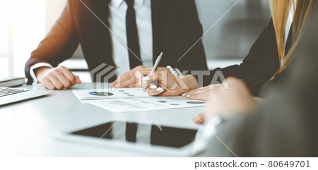 Unknown businessmen and woman sitting, working and discussing questions at meeting in sunny office, close-up. Success concept Unknown businessmen and woman sitting, working and discussing questions at meeting in sunny office, close-up. Success concept 80649701