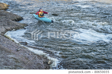 male paddler in a whitewater kayak male paddler in a whitewater kayak 80650035