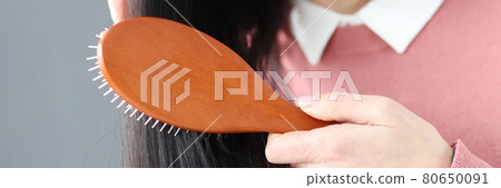 Brunette woman combs her hair with wooden comb Brunette woman combs her hair with wooden comb 80650091
