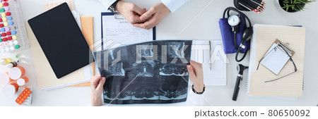 Doctor and patient are discussing the X-ray at work table Doctor and patient are discussing the X-ray at work table 80650092