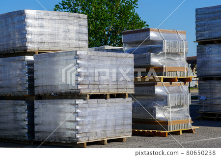 pallets stacked with cobblestones wrapped in transparent plastic film 80650238