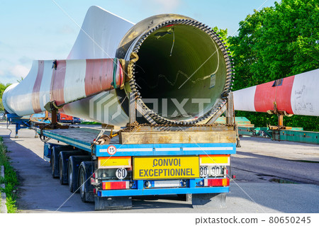 A view of a truck, a low-loader semi-trailer with oversized wind generator parts in the parking lot 80650245