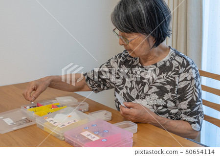 Elderly Japanese woman caring for her sick husband and sorting medicine Elderly Japanese woman caring for her sick husband and sorting medicine 80654114