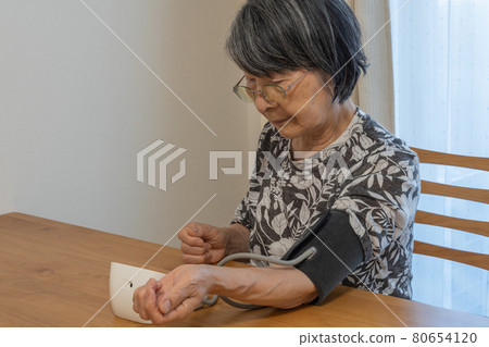 An elderly Japanese woman who shows a high value in blood pressure measurement and becomes a straight face 80654120