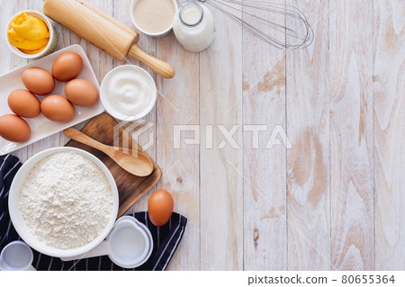 Homemade dough recipe (eggs, flour, milk, sugar) on a wooden table top view. Homemade dough recipe (eggs, flour, milk, sugar) on a wooden table top view. 80655364