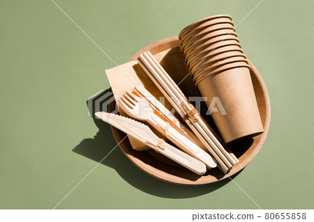 Set of Eco friendly tableware for home and picnic on green background. Plastic free. Zero waste concept. Disposable paper tableware, cups, plates, wooden forks, knives, spoons and bamboo straws Set of Eco friendly tableware for home and picnic on green background. Plastic free. Zero waste concept. Disposable paper tableware, cups, plates, wooden forks, knives, spoons and bamboo straws 80655858