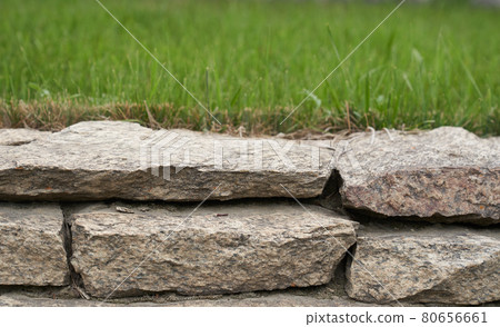Stone podium display. A natural rock pedestal with a natural green background. Stone podium display. A natural rock pedestal with a natural green background. 80656661