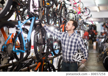active man in bicycle shop chooses for himself sports bike 80657258