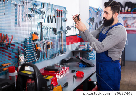attractive man worker working at restoring motorbike in workshop attractive man worker working at restoring motorbike in workshop 80657445