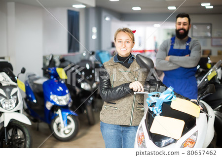 cheerful male worker assisting female customer in repairing motorcycle in workshop cheerful male worker assisting female customer in repairing motorcycle in workshop 80657462