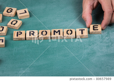 Promote. Wooden alphabet letters on a green blackboard background Promote. Wooden alphabet letters on a green blackboard background 80657989