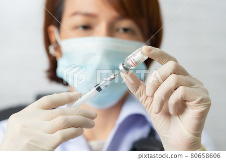 Asian medical worker, nurse in mask, hold syringe with vaccine. Covid-19, coronavirus disease, healthcare workers concept. 80658606