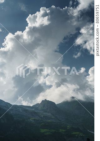 Rocks and a pass with a blue sky with sun rays breaking through the clouds. 80659751