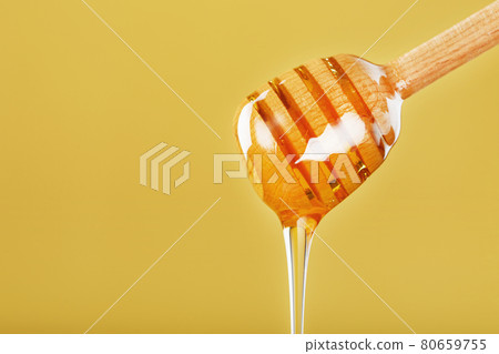Natural Honey flows down from a honey bucket on a yellow background. 80659755