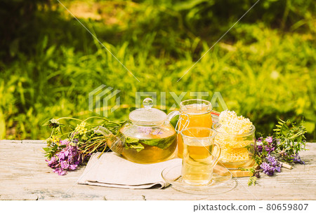 Tea with fresh lemon balm summer herbs clover leaves in glass cup and teapot on wooden rustic background 80659807