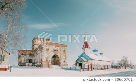 Village Lenino, Dobrush District, Gomel Region, Belarus. Old Ruined Orthodox Church Of The St. Nicholas Near New Church In Winter Day Village Lenino, Dobrush District, Gomel Region, Belarus. Old Ruined Orthodox Church Of The St. Nicholas Near New Church In Winter Day 80660701