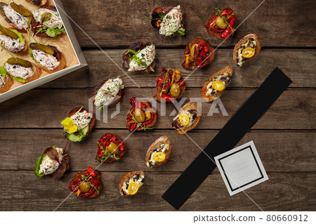 Crostini on toasted bread with toppings in carton on wooden background 80660912