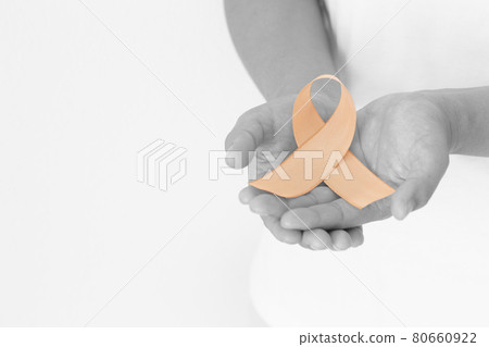 Hands holding gold ribbon on white background with copy space. The international awareness symbol for Childhood Cancer. World Cancer Day. Healthcare or hospital and insurance concept. 80660922