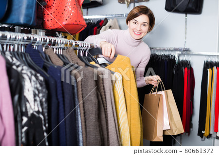 Brunette woman choosing turtleneck sweater 80661372