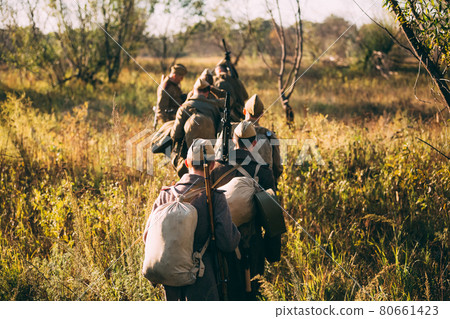 Group of unidentified re-enactors dressed as russian soldiers goes along meadow 80661423