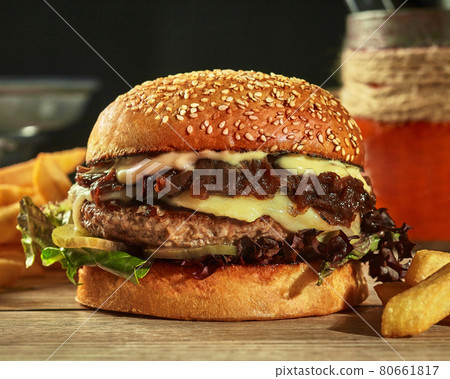 Burger with beef patty, cheese, caramelized onion, pickles and greens in sesame bun 80661817