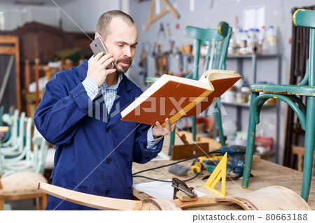 Restorer holding album and talking on phone 80663188