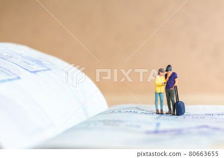 Miniature people couple standing on passport with immigration stamped , Miniature people couple standing on passport with immigration stamped , 80663655