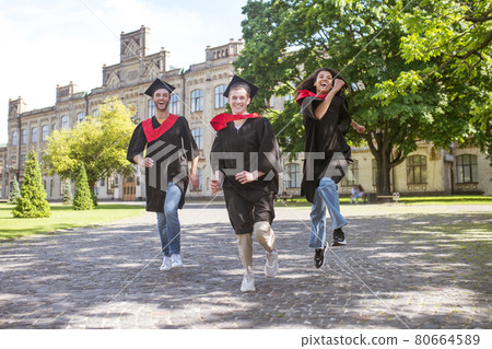 Three graduates running in the park and having fun Three graduates running in the park and having fun 80664589
