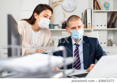 Business man in protecrive mask talking to female colleague in office 80665075