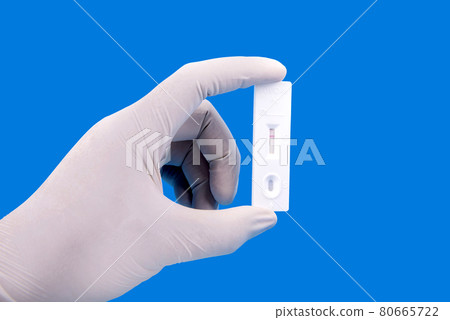 Health worker hand with protective gloves holding covid-19 antigen test kit 80665722